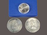 two silver coins in a blue box and a coin with a picture of a woman