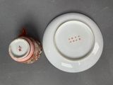 a white plate with a red design on it next to a white plate with a red design on it
