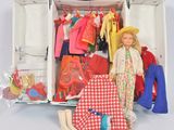 une poupée dans une valise remplie de vêtements et de chaussures