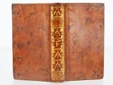 an old leather book with gold writing on it sitting on a white surface