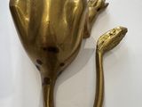 a gold frog head on a wall mounted on a white wall