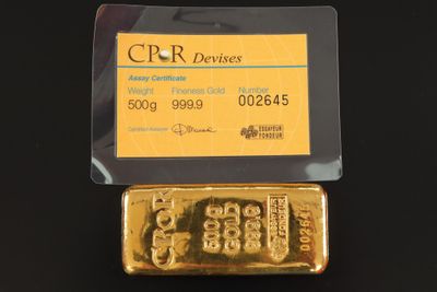 un lingot d'or et une carte de crédit posés sur une surface noire