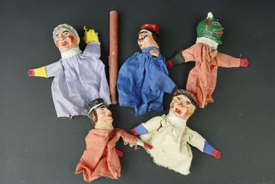 Plusieurs marionnettes représentant des personnes sont disposées en cercle sur une surface noire.