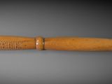 a wooden object with a wooden handle on a gray surface
