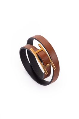 un gros plan sur un bracelet en cuir marron muni d'une boucle dorée
