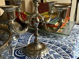 three silver candlesticks on a table with a blue and white table cloth