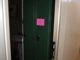 a green door with a pink sticker on it in a bathroom