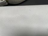 a close up of a white leather bag on a table