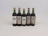 quatre bouteilles de vin sont alignées sur une surface blanche