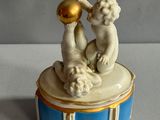 figurine en porcelaine représentant deux chérubins, posée sur une boîte bleue et blanche