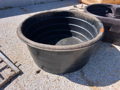 un grand pot noir posé par terre à côté d'autres objets