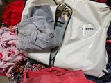 a bag of clothes that is sitting on top of a bed
