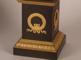 a black and gold clock with a wreath on it