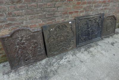 trois vieilles grilles de cheminée en fonte posées sur le trottoir