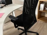 a black office chair sitting in front of a white desk