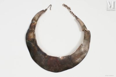une image représentant un collier muni d'une chaîne métallique posé sur une surface blanche