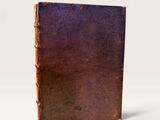 an old book sitting on top of a white table next to a white wall