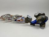 two glass fish figurines sitting on a white surface