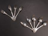 four forks and spoons are arranged in a circle on a black surface