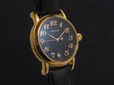 un gros plan d'une montre au cadran noir et aux aiguilles dorées