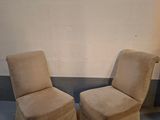 pair of beige slipper chairs sitting in a corner of a room