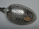 a silver spoon with a design on it sitting on a table