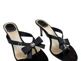 une paire de sandales noires avec un nœud au talon