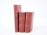 trois livres rouges empilés les uns sur les autres sur une surface blanche