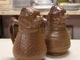 two brown vases sitting on a table in front of a picture