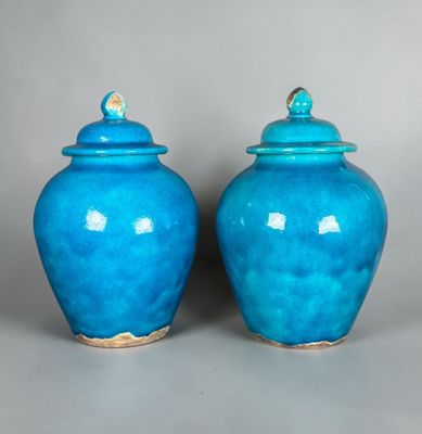 two blue vases with lids are sitting on a gray surface
