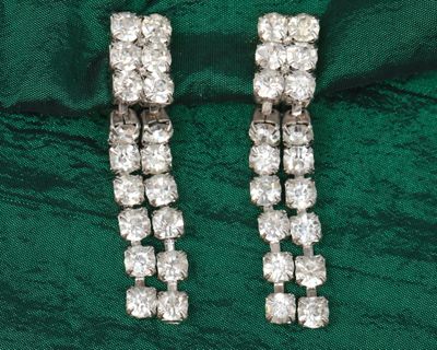 deux paires de boucles d'oreilles en diamant posées sur un fond de velours vert