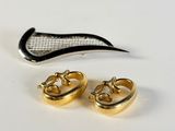 a pair of gold earrings and a pair of scissors on a white surface