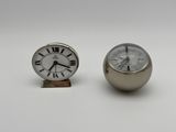 pair of small silver clocks sitting next to each other on a white surface