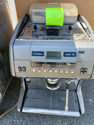 une machine à café posée par terre à côté d'une poubelle
