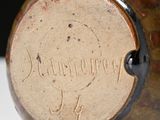 a brown vase with writing on it sitting on a table