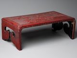 an old red table with a carved design on the top