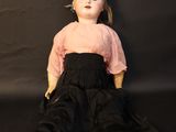 an old doll is sitting on a black surface with a black background