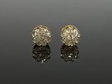 a pair of gold and diamond earrings on a reflective surface
