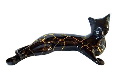 a black cat figurine laying down on a white surface