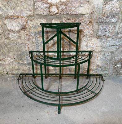 un support à trois niveaux pour plantes, avec un mur en pierre en arrière-plan