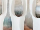 five spoons with different colors are lined up on a white surface