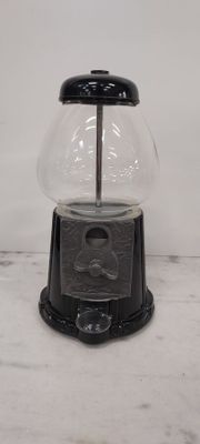 a black and clear gum ball dispenser on a marble counter top