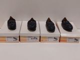 quatre paires de chaussures noires posées sur des cartons, sur une surface blanche