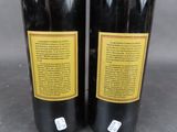 two bottles of red wine sitting on top of a table