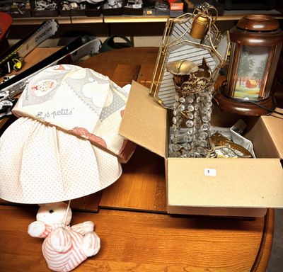 a table with a lamp, a lamp shade, a teddy bear, and other items on it