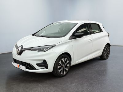 Une voiture blanche est garée dans une pièce au sol noir.