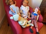three dolls that are sitting on a red chair