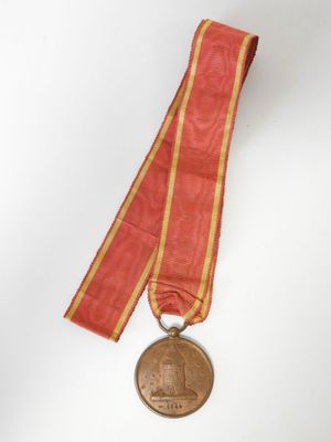 une vieille médaille entourée d'un ruban, posée sur une surface blanche