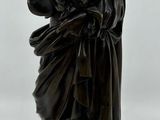 statue en bronze représentant un homme tenant un bébé dans ses bras, posée sur un socle en marbre