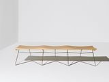 a wooden bench sitting on top of a white floor next to a wall